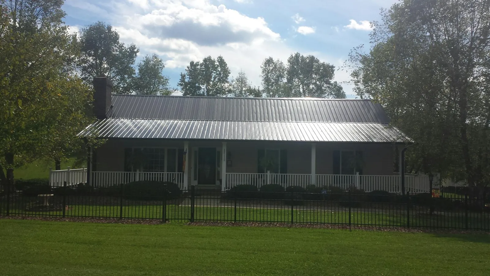Gray metal roof on a brick ranch with a full width front porch — Gutter Guard Installation work by our crew in Stoughton